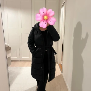 Svart lång pufferjacka med bälte - Dunjacka som går att använda både med skärp och ytan. Storlek xs