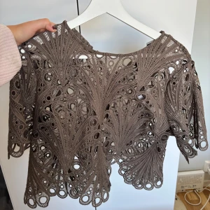 Brun spetsblus från Noella - Superfin brun blus från Noella med broderat mönster.
