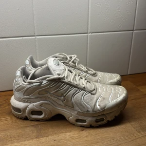 Nike vita sneakers med vågigt mönster - Nike sneakers i helvitt med vågiga detaljer och synlig Air-sula. Skorna har snörning, rund tå och är tillverkade i syntet och mesh. Den chunky sulan ger en sportig vibe och de ikoniska Nike-loggorna syns på sidorna.