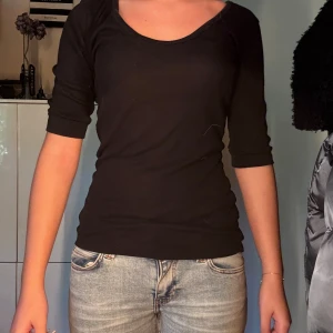 Svart ribbad topp från Zara - En svart ribbad topp från Zara med trekvartsärm och rundad, djup ringning. Sitter figurnära och är superenkel att styla till olika looks. 