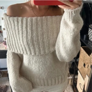 Offshoulder stickad tröja  - Supermysig stickad offshoulder-tröja i beige med bred ribbad kant upptill. Tröjan har långärmade ärmar och en loose fit. Super fin till höst o vintern