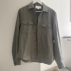 Olivgrön overshirt från Zara Origins - Olivgrön overshirt från Zara i storlek S. Skjortan är tillverkad i linne, har klassisk krage, två bröstfickor med lock och knappar framtill. Långärmad modell med knappar vid ärmslut. Perfekt för lager-på-lager och chill stil. Även fet nu inför hösten. Endast andvänd 1 gång.