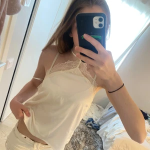 Vit linnetopp med spetsdetaljer - Säljer en söt vit linnetopp med tunna axelband och fina spetsdetaljer upptill. Toppen har en halterneck-modell och är tillverkad i ett mjukt, lätt material som passar perfekt till sommaren.                   Är typ som i ”siden” material. Passar xs-s. Pris kan diskuteras vid snabb affär