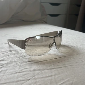 Vita solglasögon med strass - Snygga solglasögon med vita skalmar och stora, silvriga spegelglas. Glasen har en wraparound-form och är dekorerade med små strasstenar i hörnen för extra bling och y2k känsla 🤍