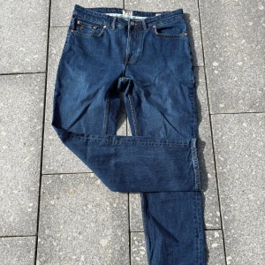 Morris blå jeans 33/32 - Snygga blå jeans från Morris i klassisk femficksmodell. Jeansen har raka ben, normal passform och detaljer i kopparfärg vid fickorna. Tillverkade i slitstark bomullsdenim med läderpatch bak i midjan.