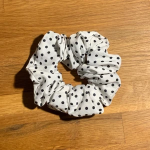 Fyra scrunchies  - Säljer fyra scrunchies: en vit med svarta prickar i mjukt tyg, två glittriga vita/silverfärgade  och en lila gjord från två olika materia. Den lila är däremot inte så stretchig. 