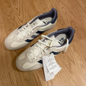 Adidas Gazelle vita och marinblå sneakers - Säljer ett par Adidas Gazelle sneakers i vitt och marinblått. Helt oanvända.