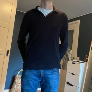 Svart långärmad pikétröja These Glory Days - Mörk, svart långärmad pikétröja från These Glory Days i storlek small. Klassisk krage med knappar och mjukt material som känns skönt mot huden. Perfekt för dig som gillar stilrena och enkla plagg med en avslappnad vibe.