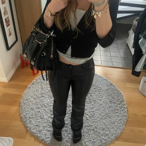 Svarta skinnbyxor från BikBok - Trendiga snygga byxor i skinnimitation. Byxorna har normal passform och midja, perfekt till en cool vardagslook. Stängs med knapp och dragkedja framtill.