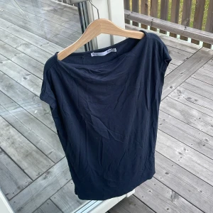 mörkblå t-shirt från 157, S - mörkblå t-shirt från 157 i storlek S. Modellen har en bred, lite båtformad halsringning och korta ärmar. T-shirten är gjord i mjuk bomull och har en clean, enkel look utan mönster eller detaljer. Perfekt för dig som gillar minimalistisk stil.
