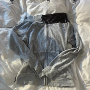 Grå offshoulder hoodie med dragkedja - Grå hoodie med dragkedja och offshoulder-design. Tröjan har en bred ribbad kant upptill och en mörkare grå detalj vid axeln. Långärmad och med fickor framtill, perfekt för en chill och avslappnad look.💕