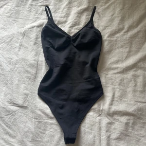 Svart bodysuit med smala axelband från H&M - Säljer en svart bodysuit från H&M med smala axelband och v-ringning. Använt en gång och i fint och rent skick, har vanligtvis xs den är väldigt liten i passformen, pris kan diskuteras