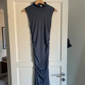 Mörkblå långärmad klänning från Zara - Säljer en lång, mörkblå ärmlös klänning från H&M i ribbad polyester. Klänningen har hög hals och en tight passform som framhäver siluetten. 