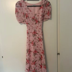 Ljusrosa blommig långklänning - Superfin ljusrosa långklänning med blommigt mönster och puffiga korta ärmar från Cubus i storlek 36. Använd 2 gånger. 175kr