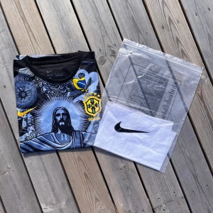 Brasilien Fotbollströja - Säljer en riktigt snygg Brasilien fotbollströja som är i helt nytt skick med etikett, förpackning och är helt oanvänd. Den är i storlek S och är i färgen Svart/vit med gula detaljer. Pris:349kr men priset är inte hugget i sten. 