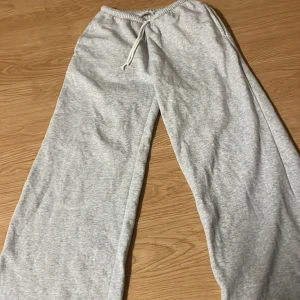 Grå mjukisbyxor med snörning - Ljusgrå mjukisbyxor från C i storlek 134/140. Byxorna har resår i midjan och snörning för extra komfort. Tillverkade i mjukt material som passar perfekt för chill dagar. Raka ben och enkel design gör dem lätta att matcha med allt.