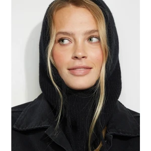 Svart stickad balaclava med snörning - Säljer en svart ribbstickad balaclava med huva och snörning framtill. Den är gjord i mjukt stickat material och täcker både hals och huvud, perfekt för kalla dagar. Enkel, stilren design som funkar till jacka eller hoodie. Ligger i original förpackning med prislappen kvar!