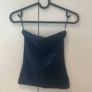 Mörkblå ribbad linnetopp S - Säljer en stilren mörkblå ribbad linnetopp i storlek S. Toppen har tunna axelband och en enkel, rak passform som ger en clean look. Perfekt att matcha med jeans eller kjol för en trendig outfit.