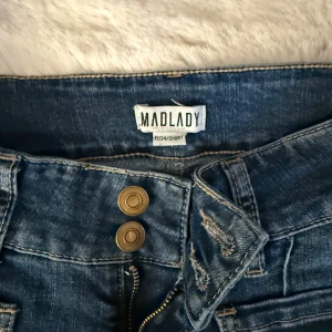 Bootcut jeans från Madlady, blå - Snygga blå bootcut jeans från Madlady i storlek EU34/Short. Jeansen har två framfickor, två bakfickor med knappdetalj och dubbla knappar i midjan. Materialet är klassisk jeans med lätt slitning och markerade sömmar. Passar mig som är 162 perfekt i längden!