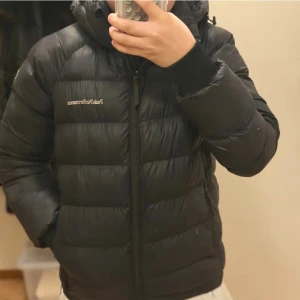 Helt ny!Svart dunjacka Peak Performance 140 - Tveka inte att höra av er! Aktiv hela dagen Säljer en svart dunjacka från Peak Performance i storlek 140. Jackan har huva, dragkedja framtill och två sidofickor med dragkedja. Klassisk pufferstil med breda kanaler och diskret logga på bröstet. Perfekt för kalla dagar.