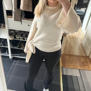 Beige stickad tröja - Strl S, fint skick och använd få gånger. Knytdetalj på ena sidan. Fel i tyget på ryggen där det är lite mörkare men inget som syns när håret är nere. 