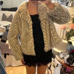 Pälsjacka  - Beige/vit/grå pälsjacka med en brosch framtill. Storlek 11-12 år men passar Xs-S