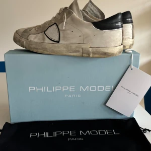 Philippe Model vita sneakers med svart detalj - Tjena!! Säljer mina trendiga Philippe model pågrund av att dem inte kommer till någon användning längre. Skorna har tecken på användning men har mycket kvar att ge. Allt kommer med dvs skor, box, dustbag och Philippe model kort.   Kvitto kan få skickats vid intresse!!!  Hör av dig vid fler frågor👊
