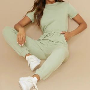 Ljusgrön jumpsuit med snörning. Från PLT - En stilren ljusgrön jumpsuit i mjukt bomullsmaterial med kort ärm och rund hals. Byxorna har normal passform, resår och snörning i midjan samt fickor på sidorna. Perfekt för en chill och avslappnad look. Knappt använd. 