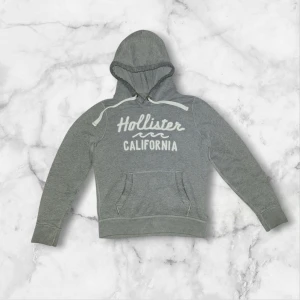Vintage Hollister Hoodie  - Tjena! Säljer nu denna stilrena gråa hoodien från Hollister. Hoodien är trots sin ålder i mycket gott skick, och jag ser inget att anmärka på för den delen. Sitter normalt i storleken, kan troligtvis även passa S.  Kontakta mig vid frågor! OBS pris kan diskuteras!