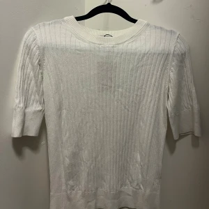 Vit ribbad stickad tröja - Snygg vit stickad tröja med ribbat mönster och kortare ärmar. Perfekt för dig som gillar en clean och stilren look. 