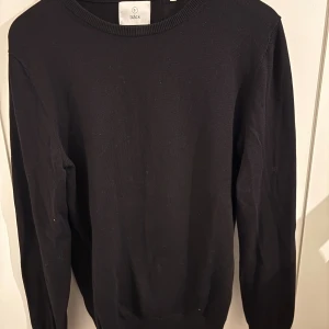 Svart stickad tröja från Bläck - En stilren svart stickad tröja från Bläck i storlek S. Tröjan har rund halsringning och långa ärmar, perfekt för lager-på-lager eller som den är. Enkel och klassisk design som funkar till det mesta.