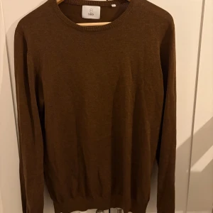 Brun stickad tröja från Bläck - Snygg brun stickad tröja från Bläck i storlek M. Tröjan har rund halsringning och långa ärmar, perfekt för lager-på-lager. Materialet är mjukt och skönt, och den neutrala färgen gör den enkel att matcha med jeans.