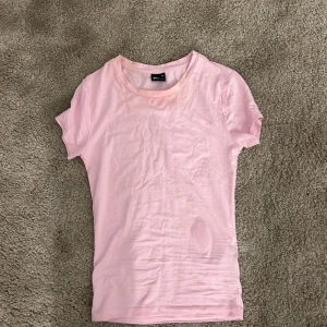 Ljusrosa t-shirt från Gina Tricot XS - En basic ljusrosa t-shirt från Gina Tricot i storlek XS. T-shirten har rund halsringning och korta ärmar, tillverkad i mjuk bomull. Perfekt för en enkel och avslappnad stil. Den är inte använd så mycket, men när jag testar den har den fått lite sminkfläckar som förmodligen kommer gå bort i tvätten.