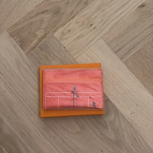 Orange plånbok  - Orange plånbok med motiv av tennisspelare. 