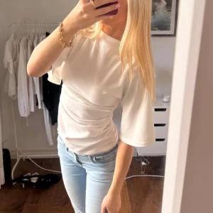 Vit topp från Bohoo - Toppen har en mjuk, lätt struktur och sitter normalpassad. Perfekt att styla med jeans eller kjol för en fräsch look. Framhäver midjan och har en enkel, clean design. Stl 36/S.
