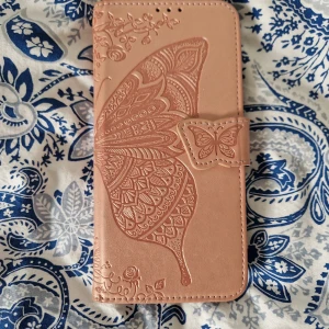 Butterfly Wallet Case för OnePlus Nord n100 - Elegant rosa plånboksfodral med vackert fjärilsmönster Fodralet har 4 kortplatser och magnetlås. Skicket är bra men har använts.