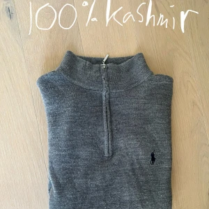 Grå kashmirtröja Polo Ralph Lauren - Supermjuk grå polotröja i 100% kashmir från Polo Ralph Lauren. Tröjan har en halv dragkedja, ribbad krage och långa ärmar. Klassisk broderad logga på bröstet. Perfekt för lager-på-lager och chill stil. Storlek L men passar mer M-S tröjan har dock inte krympt i tvätten. Enda defekten är lappen i nacken har lossnat på en sida, annars mycket bra skick!