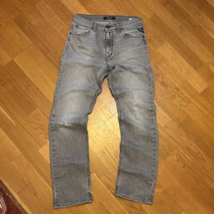 Replay ljusgrå jeans straight fit - Säljer ett par ljusgrå jeans från Replay med klassisk femficksdesign och snygga detaljer på bakfickorna. Jeansen har rak passform och är tillverkade i slitstarkt denim. Perfekta för dig som gillar en avslappnad och stilren look.