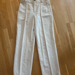 Beiga / vita / cremevita kostymbyxor från Zara - Snygga beiga / vita  kostymbyxor från Zara i storlek M. Byxorna har hög midja, raka ben och pressveck framtill. Väldigt snygga och använda endast fåtal gånger 