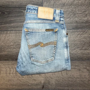 Nudie Jeans Skinny Lin - Ljusblå jeans från Nudie Jeans, modell Skinny Lin. Slimmad passform med skinny stil och klassisk femficksdesign. Tillverkade i 98% ekologisk bomull och 2% elastan för extra stretch. Midja 35, längd 95,5cm. JAG SKICKAR EJ FLER BILDER NÄR JAG BÄR JEANSEN! för storleksguide hänvisar jag till måtten och för bättre inblick i passformen rekommenderar jag att googla på modellnamnet. Jeansen kan vara uppsydda utan att jag noterat det så kolla måtten noggrant :) s3