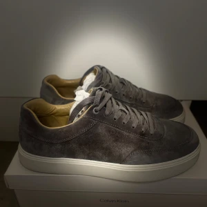 Calvin Klein mockasneakers - Snygga  sneakers från Calvin Klein i mjuk mocka med beige innersida och vit platt sula. Ny pris 1600kr. Perfekt för dig som gillar stilrena och minimalistiska skor med premiumkänsla.