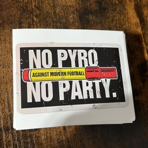Perfekta ultras klibbor för dig som supportar ett lag. - Bilderna visar ett stort antal klistermärken med texten 'NO PYRO NO PARTY' och 'AGAINST MODERN FOOTBALL'. Klistermärkena är i nyskick och har en färgstark design med svart bakgrund och vit text. Perfekt för fans och supporterkultur. Inga synliga defekter eller slitage.