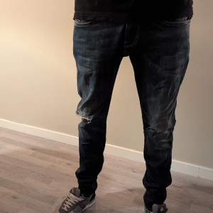 Anbass Replay jeans med slitningar - Säljer ett par mörkblå jeans från Replay med  slitningar på knäna. Jeansen är slitna men jättesköna och stretchiga.stl. 32/32