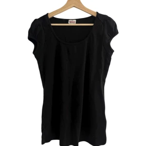 Svart kortärmad topp från colors of the world - En svart enkel topp från Cowboysbelt med rund halsringning och korta puffärmar. Tillverkad i mjuk bomull som känns skön mot huden.