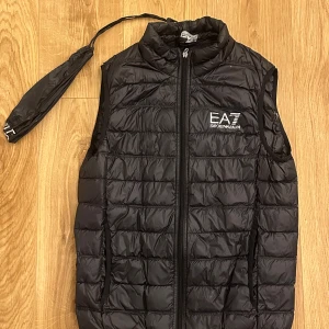 Svart dunväst från EA7 Emporio Armani - Snygg svart dunväst från EA7 Emporio Armani, kommer med förvaringspåse, knappt använd