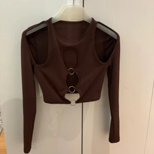 Brun croppad topp med ringdetaljer - Säljer en jätte snygg brun långärmad croppad topp perfekt för en utgång.