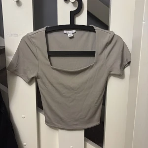 Beige croppad topp från new yorker - Säljer en beige croppad topp från Amisu i storlek S. Toppen har korta ärmar och en fyrkantig, lite djupare halsringning som ger en snygg look. Materialet är mjukt och stretchigt. Den är nästan bara använd 2 gånger men säljer billigt eftersom den ej kommer till användning.