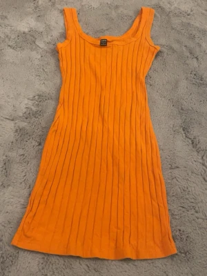 Ribbad orange klänning från Shein - Säljer en snygg orange ribbad klänning från Shein i storlek S. Klänningen är ärmlös med breda axelband och har en kroppsnära passform. Perfekt för sommarens alla tillfällen och enkel att styla med sneakers eller sandaler. Kan eventuellt tänka mig gå ner i pris