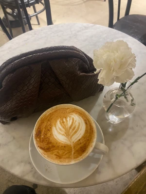 Brun kuvertväska i skinn - Snygg brun kuvertväska med flätad struktur och unik form. Väskan är tillverkad i skinn och har ett coolt, trendigt utseende som sticker ut. Perfekt att bära under armen och passar till många olika outfits.