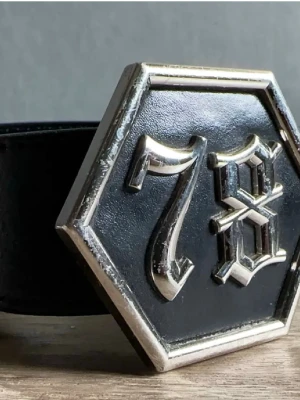 Bälte skärp  - Säljer ett svart skärp med ett rejält sexkantigt metallspänne i silver. Skärpet är gjort i slätt skinn och har en klassisk look med markerade sömmar. Perfekt för att ge outfiten en cool edge.